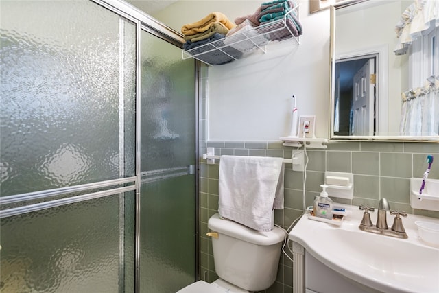 bathroom featuring vanity, a shower with door, toilet, and tile walls