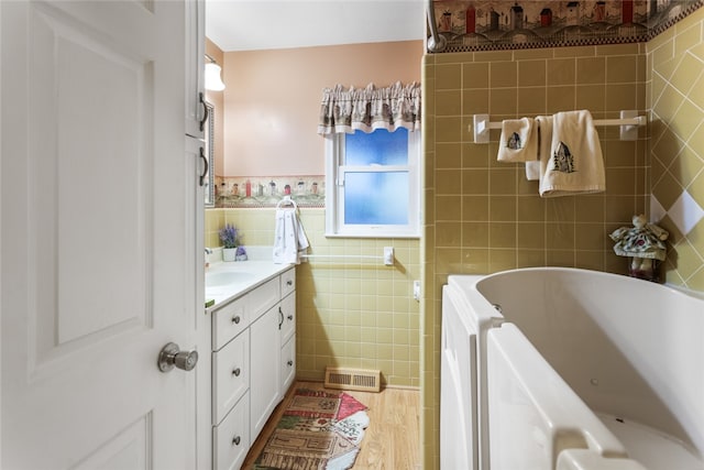 bathroom featuring vanity, a tub to relax in, and tile walls