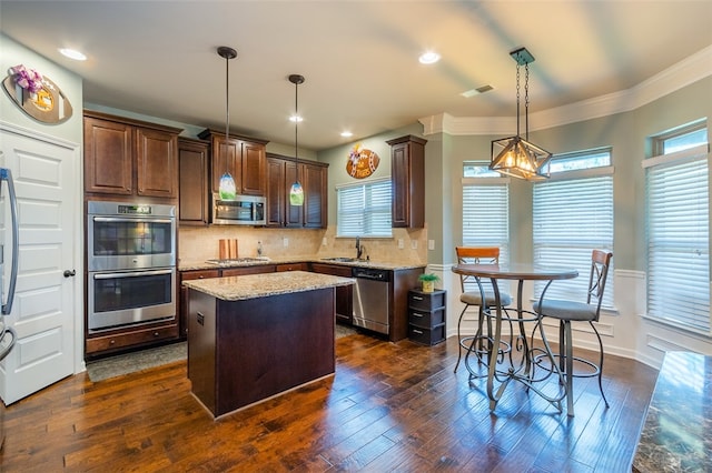 kitchen featuring dark wood-type flooring, tasteful backsplash, decorative light fixtures, a kitchen island, and appliances with stainless steel finishes