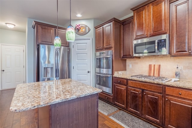 kitchen with a center island, hanging light fixtures, dark hardwood / wood-style floors, and appliances with stainless steel finishes