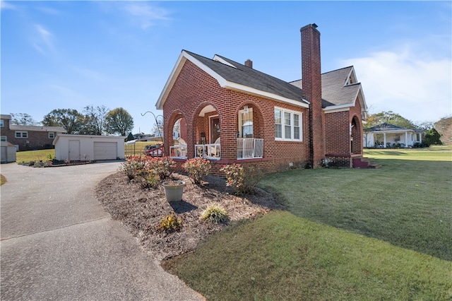 view of front facade with a garage, a porch, an outbuilding, and a front lawn