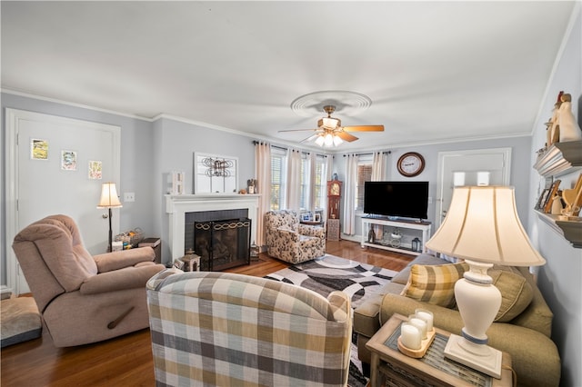 living room with hardwood / wood-style floors, a brick fireplace, ceiling fan, and crown molding