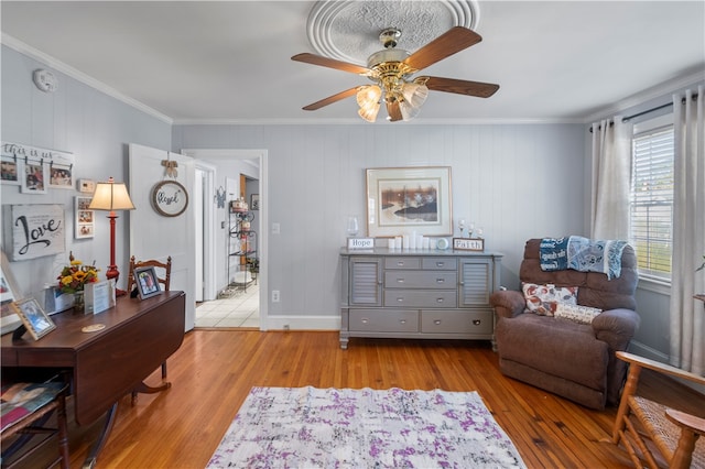 living area with light hardwood / wood-style floors, ceiling fan, and crown molding