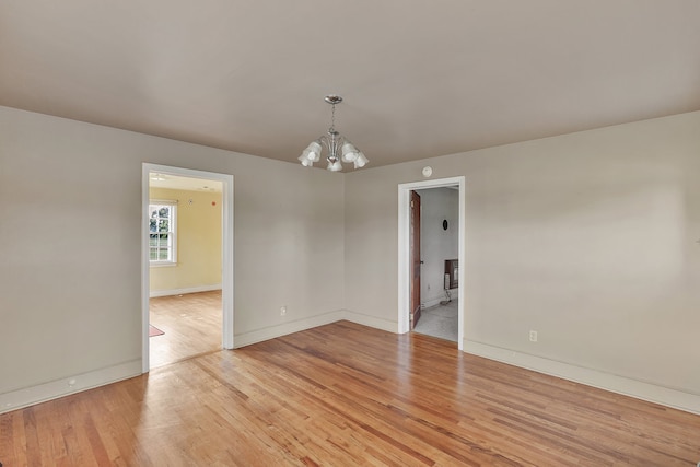 unfurnished room featuring light wood-type flooring and a notable chandelier