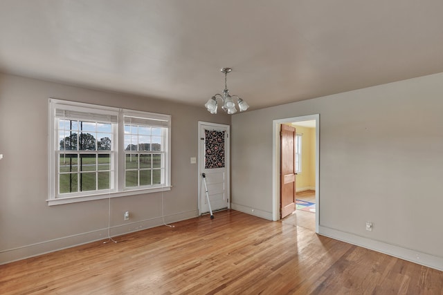 unfurnished dining area with light wood-type flooring and an inviting chandelier