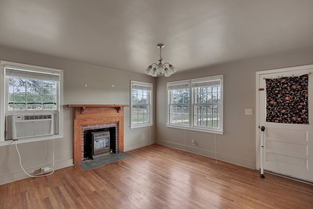 unfurnished living room featuring a chandelier, hardwood / wood-style floors, and a brick fireplace