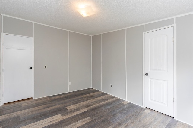 unfurnished room with a textured ceiling and dark hardwood / wood-style floors