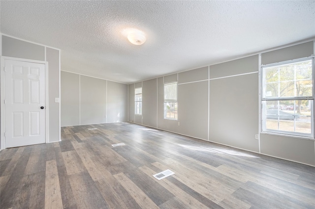 unfurnished room with hardwood / wood-style floors and a textured ceiling