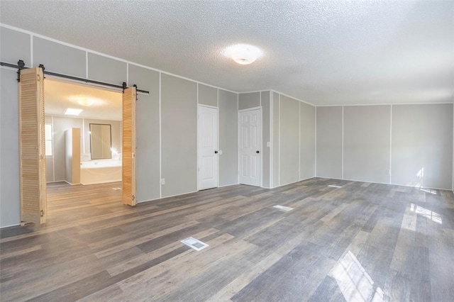 182 Poplar Springs Dr, Easley, SC 29642 - unfurnished room with a barn door, wood finished floors, a textured ceiling, and a decorative wall