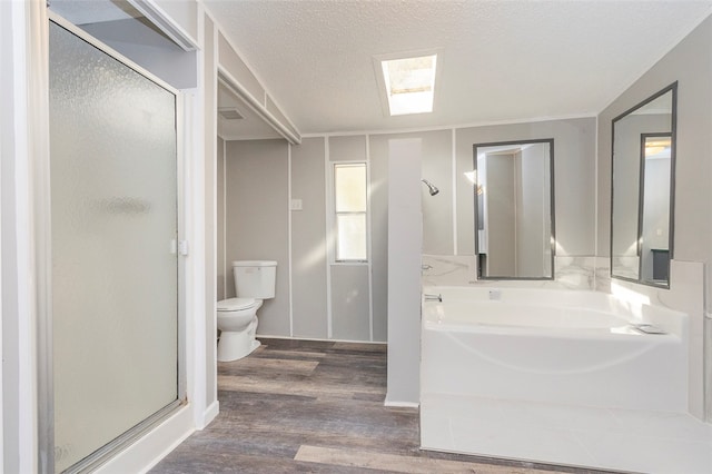 bathroom featuring a skylight, hardwood / wood-style flooring, separate shower and tub, toilet, and a textured ceiling