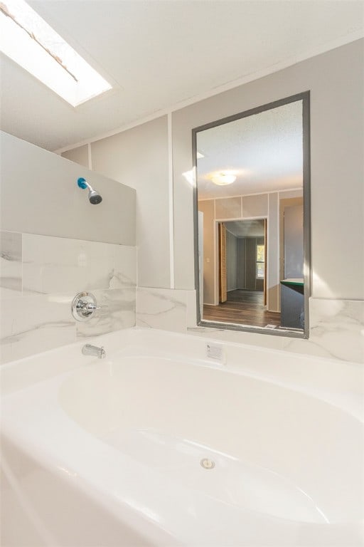 bathroom featuring a bath and a skylight