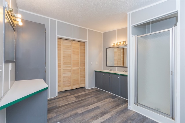 bathroom with vanity, hardwood / wood-style flooring, ornamental molding, a textured ceiling, and a shower with shower door