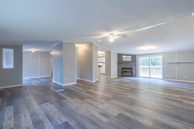 unfurnished living room with ceiling fan, a fireplace, dark wood-type flooring, and a textured ceiling