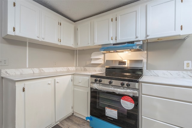 kitchen with white cabinetry, stainless steel stove, light hardwood / wood-style floors, and a textured ceiling