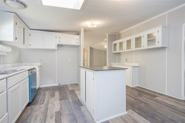 kitchen featuring stainless steel dishwasher, a textured ceiling, crown molding, wood-type flooring, and white cabinetry