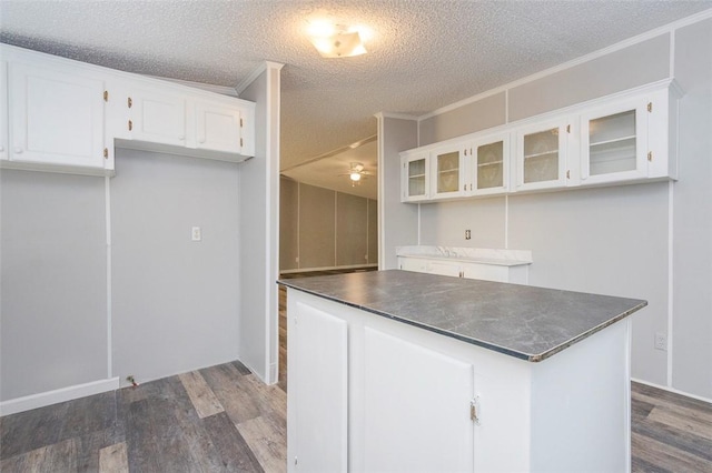 182 Poplar Springs Dr, Easley, SC 29642 - kitchen with dark wood-style flooring, white cabinetry, dark countertops, glass insert cabinets, and crown molding