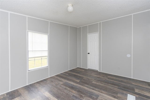 unfurnished room featuring dark wood-type flooring and a textured ceiling