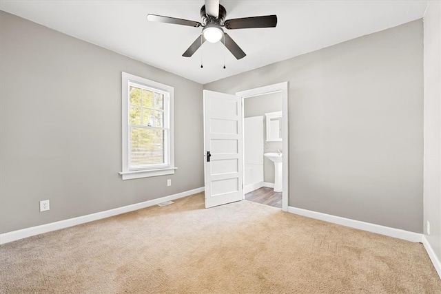 unfurnished bedroom featuring ceiling fan, light colored carpet, and ensuite bathroom