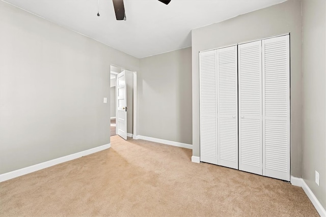 unfurnished bedroom with ceiling fan, light carpet, and a closet