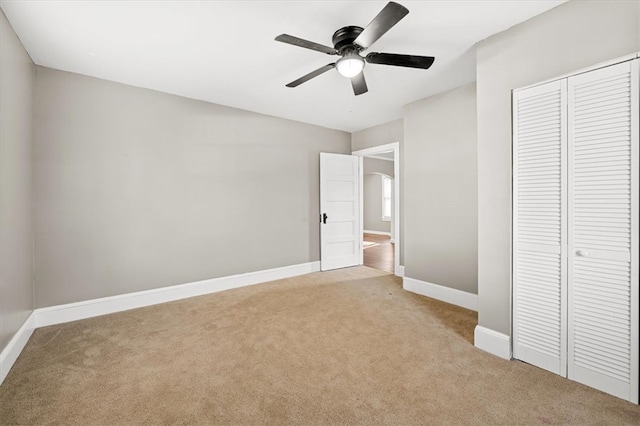 unfurnished bedroom with light carpet, a closet, and ceiling fan