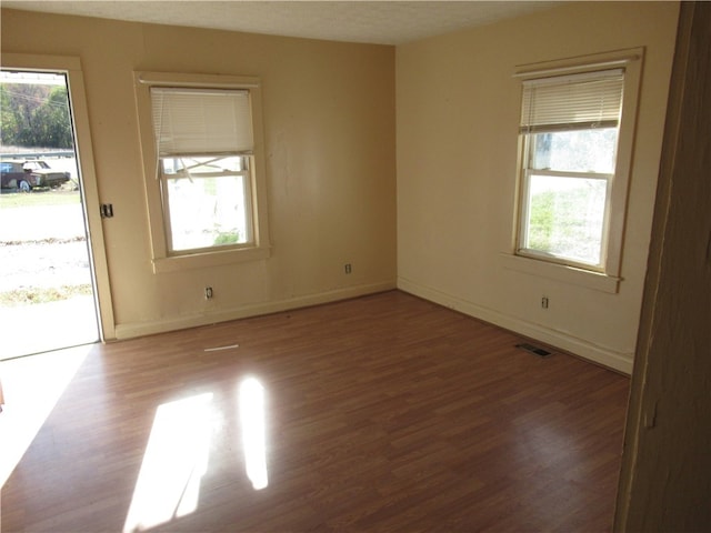 unfurnished room with hardwood / wood-style floors, a textured ceiling, and a healthy amount of sunlight