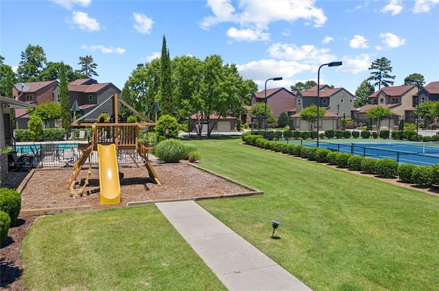 view of playground featuring tennis court and a yard