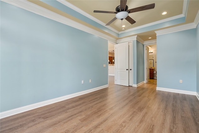 spare room with ceiling fan, light wood-type flooring, ornamental molding, and a tray ceiling