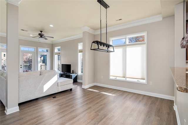 unfurnished living room with wood-type flooring, a wealth of natural light, ornamental molding, and ceiling fan