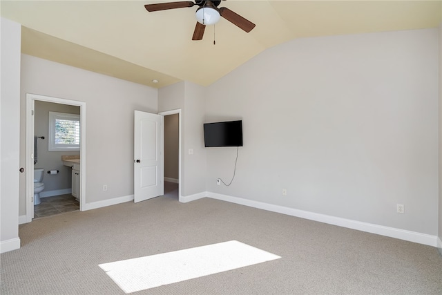 unfurnished bedroom featuring connected bathroom, ceiling fan, light colored carpet, and lofted ceiling