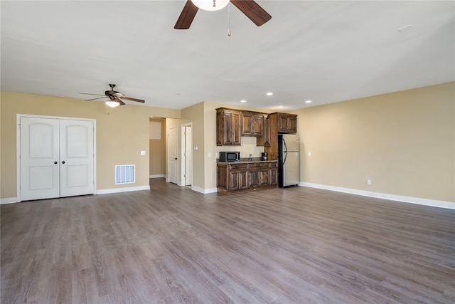 unfurnished living room featuring wood-type flooring and ceiling fan