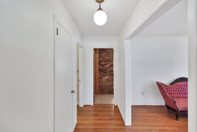 hall with hardwood / wood-style flooring and brick wall