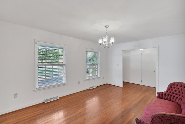 unfurnished room with hardwood / wood-style flooring and a notable chandelier