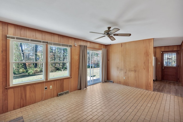 unfurnished room featuring wood walls and ceiling fan