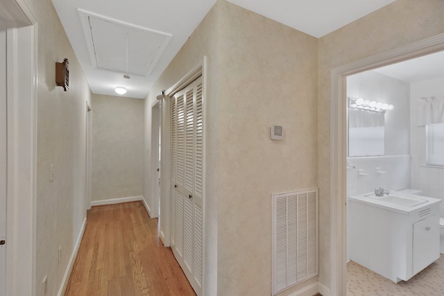 hallway with light hardwood / wood-style flooring and sink