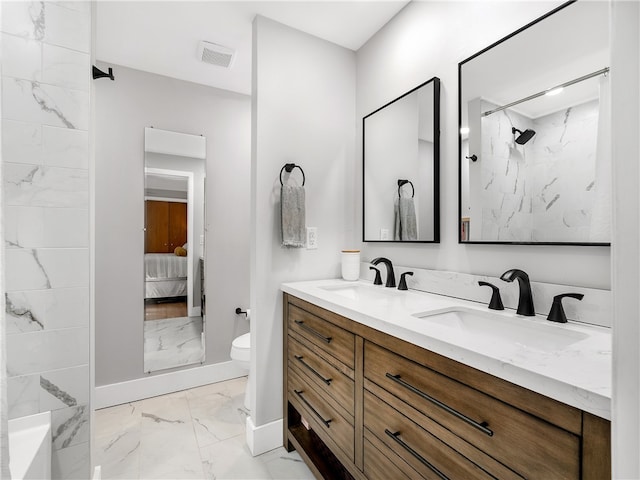 bathroom featuring a tile shower, vanity, and toilet