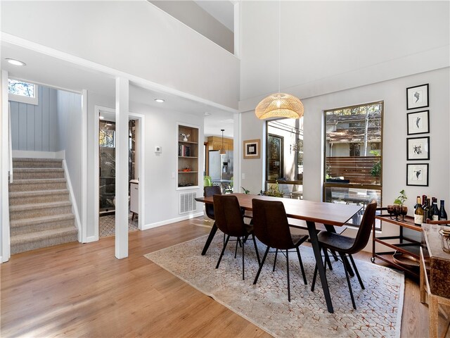 dining space featuring a high ceiling, light hardwood / wood-style floors, and built in features