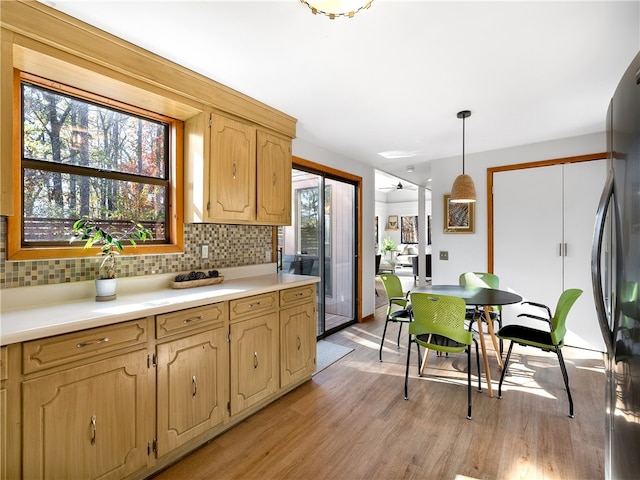 kitchen with light wood-type flooring, tasteful backsplash, ceiling fan, decorative light fixtures, and fridge