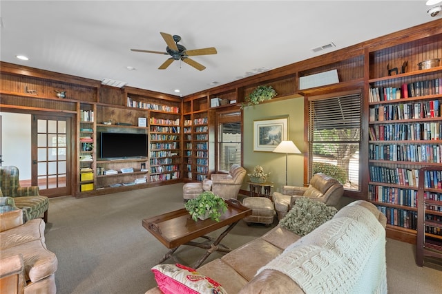 living room with ceiling fan, built in features, carpet floors, and wood walls