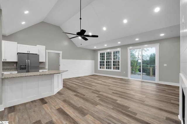 kitchen featuring light hardwood / wood-style flooring, ceiling fan, stainless steel fridge, light stone countertops, and white cabinetry