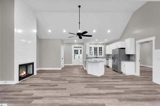 kitchen with a fireplace, stainless steel appliances, ceiling fan, white cabinets, and light hardwood / wood-style floors