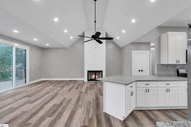 kitchen with light stone counters, a large fireplace, and white cabinets