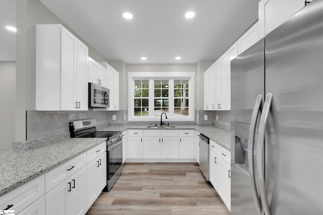 kitchen with light stone countertops, white cabinetry, and appliances with stainless steel finishes