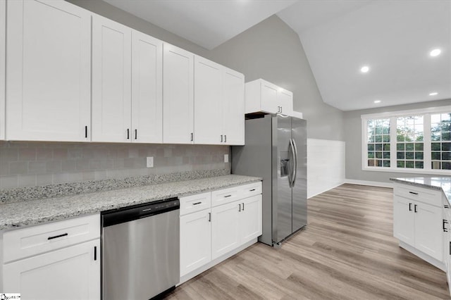 kitchen featuring white cabinets, vaulted ceiling, decorative backsplash, appliances with stainless steel finishes, and light hardwood / wood-style floors