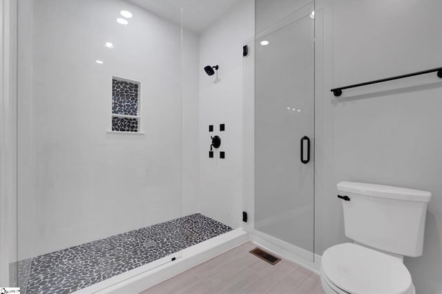 bathroom featuring toilet and a shower with shower door