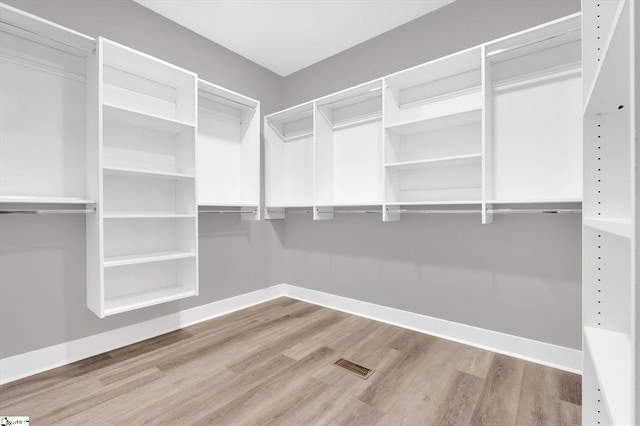 walk in closet with light hardwood / wood-style floors