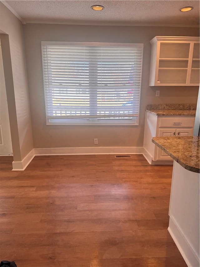 unfurnished dining area with dark wood-type flooring, a textured ceiling, and plenty of natural light