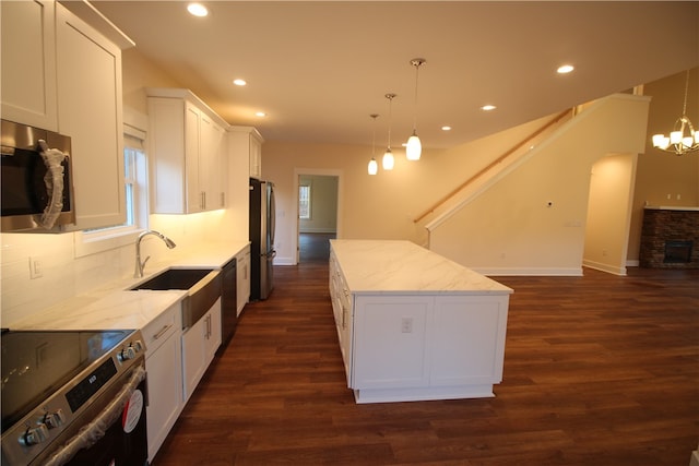 kitchen featuring decorative light fixtures, a kitchen island, white cabinetry, and stainless steel appliances