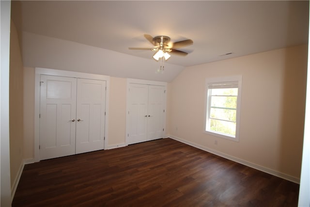 unfurnished bedroom with multiple closets, ceiling fan, dark hardwood / wood-style floors, and lofted ceiling