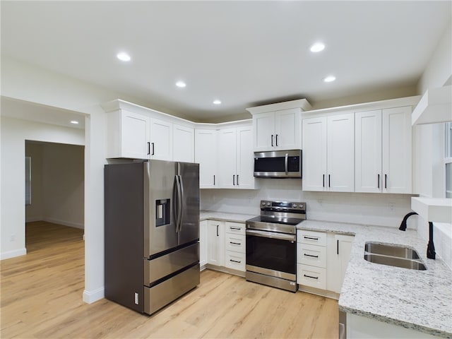 kitchen with light hardwood / wood-style floors, white cabinetry, sink, and appliances with stainless steel finishes