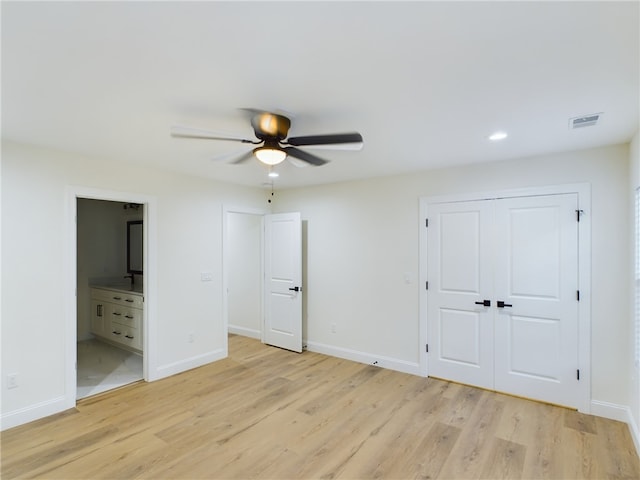 unfurnished bedroom with light wood-type flooring, a closet, ceiling fan, and connected bathroom